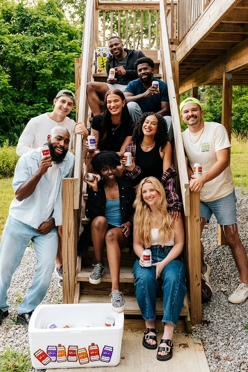 A group of people sitting together, enjoying Stoop Dayz soda in various flavors.