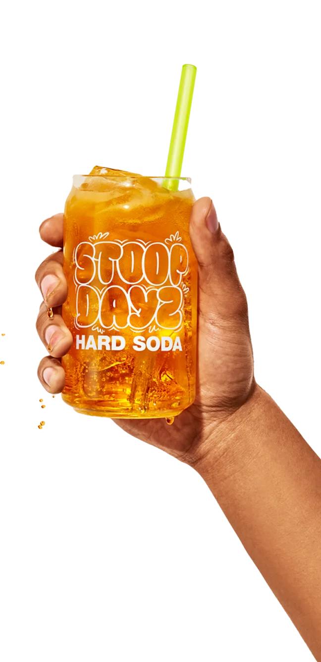 Person holding a glass of Orange Stoop Dayz Hard Soda with ice and a straw
