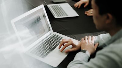 This picture shows a man sitting at a laptop and looking at the screen. It is used to illustrate the article Sending Email from "AWS: A Step-by-Step Guide to Amazon SES Integration".