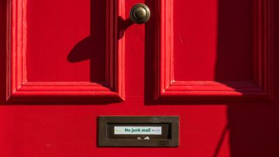 This picture shows a red front door with "No junk mail" written on the mail slot. It is intended to illustrate the article "Best Practices for Using Amazon SES: Authentication, Compliance, and List Hygiene".