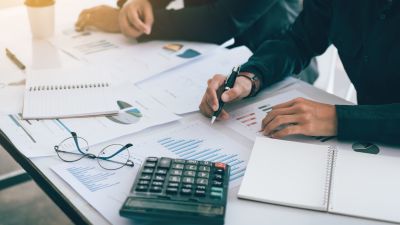 This picture shows two Persons at a desk, working on their accounting. It is used to illustrate the article: "Understanding AWS SES Pricing for Efficient Email Campaigns".