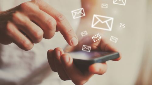 This image shows a person sending emails via their smartphone. It is meant to illustrate how helpful the use of AWS SES can be for a company's email communication with customers. 