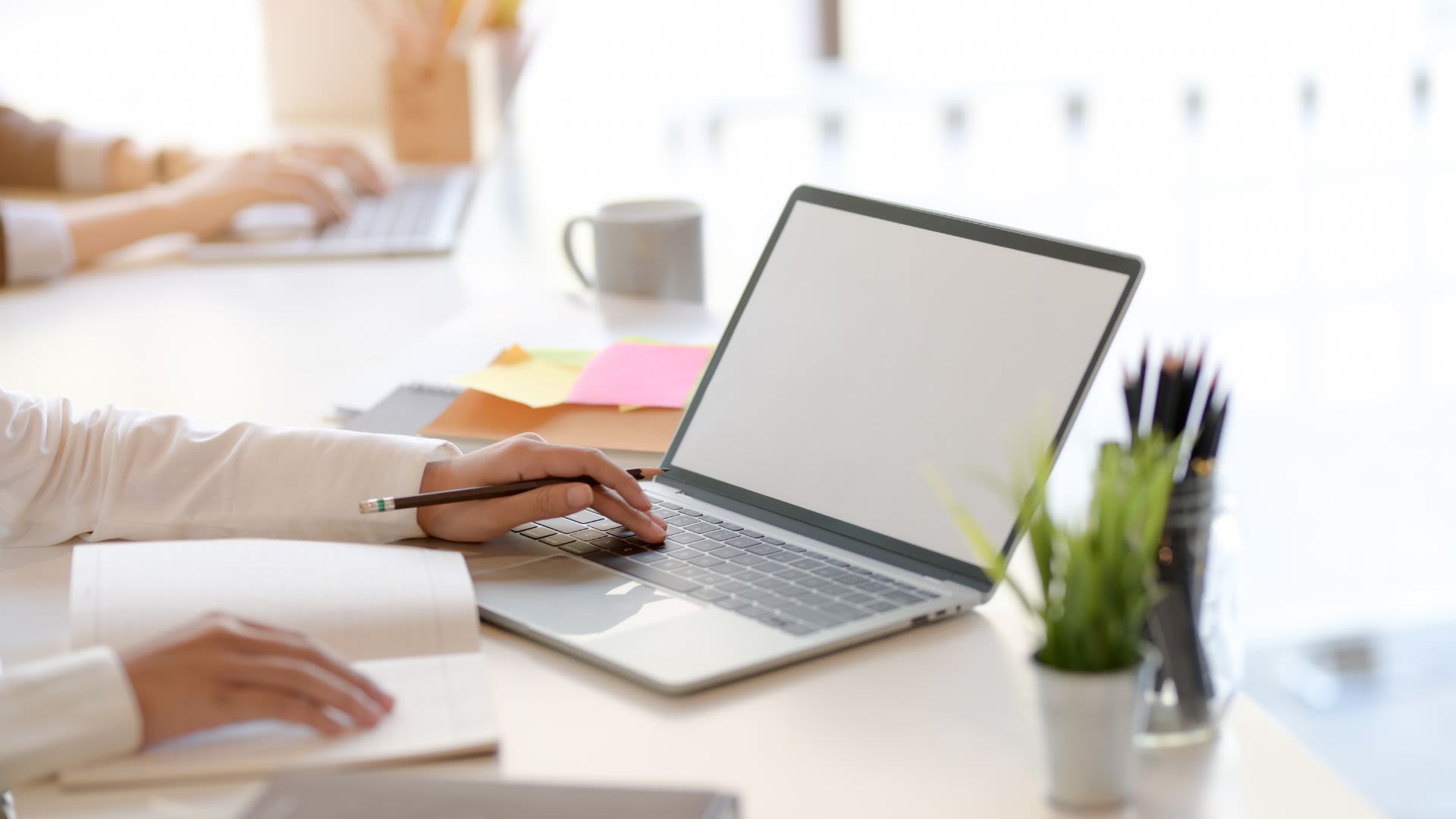 This image shows a person sitting at a laptop and taking notes on the side. It is meant to symbolize the process of creating a good transactional email. 