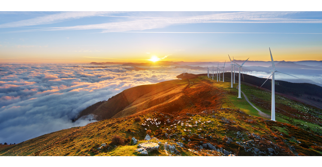 A sunset over mountains with wind turbines.