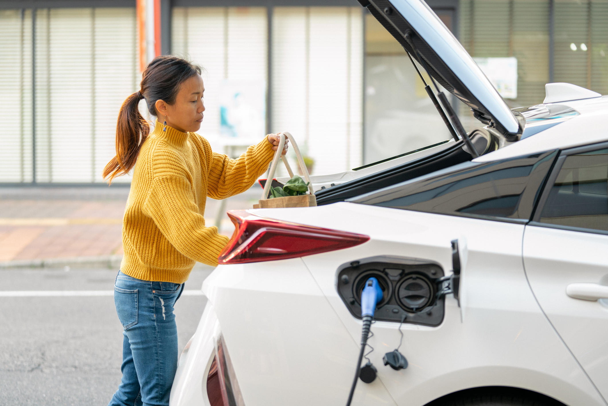 Woman putting groceries in the trunk of her electric car