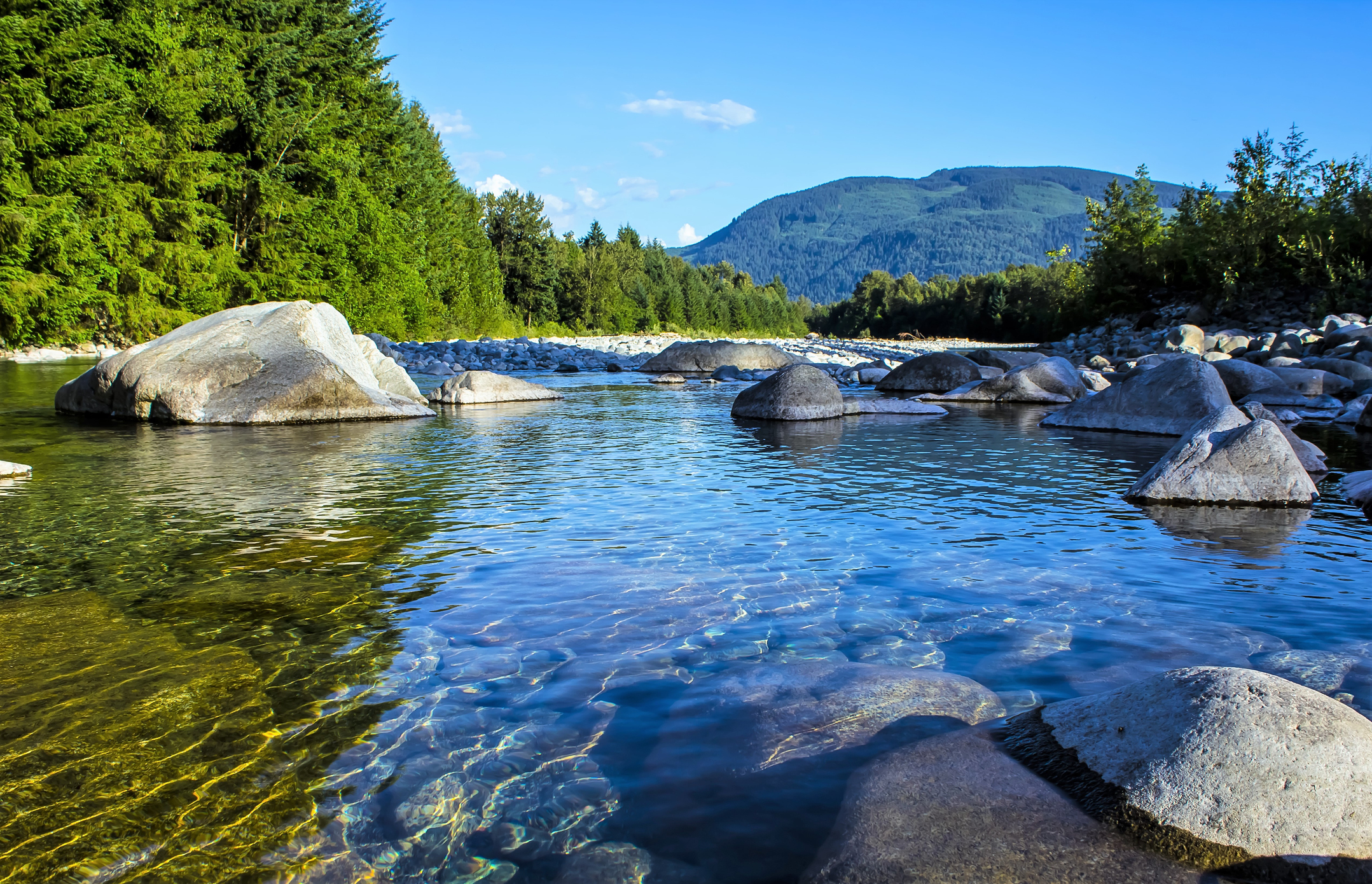 A clear stream running through mountains and forests. 