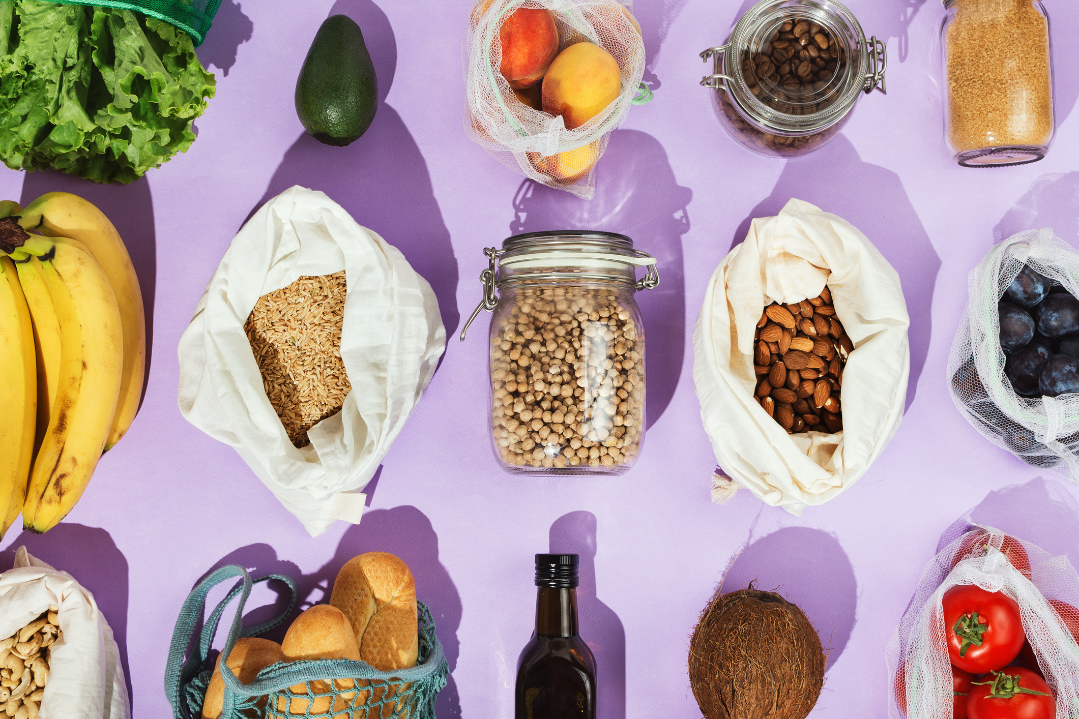 Various foods in plastic-free containers over a purple backdrop.