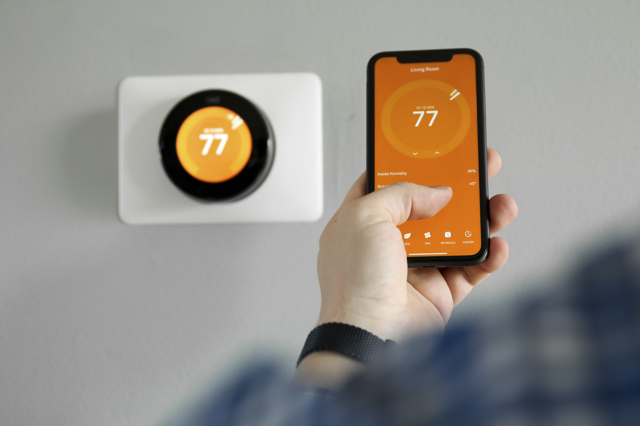Person adjusting smart thermostat in their home