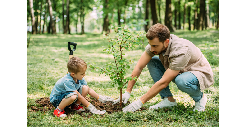 A man and child planting a tree to reduce their carbon footprint.