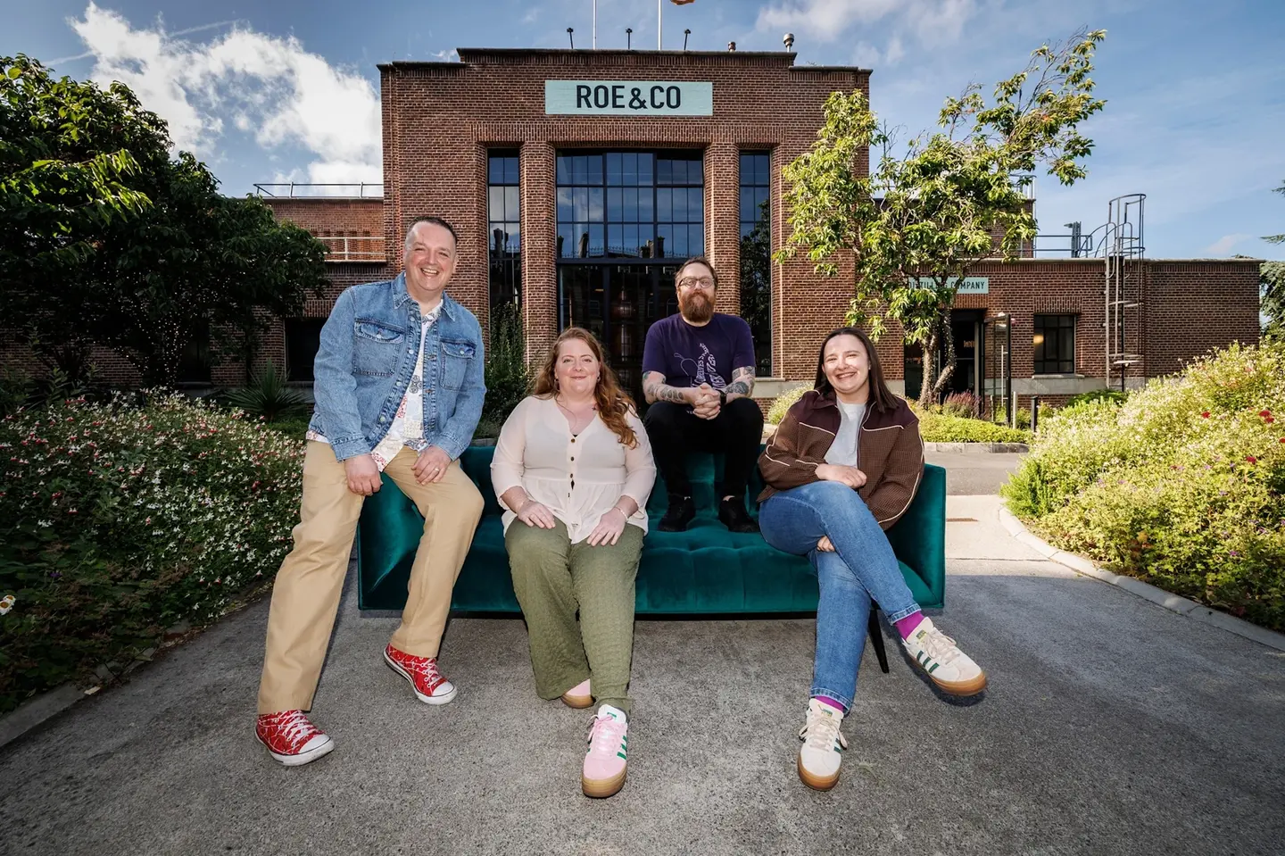 Group of people sitting outside Roe & Co Distillery, enjoying a sunny day in the garden.