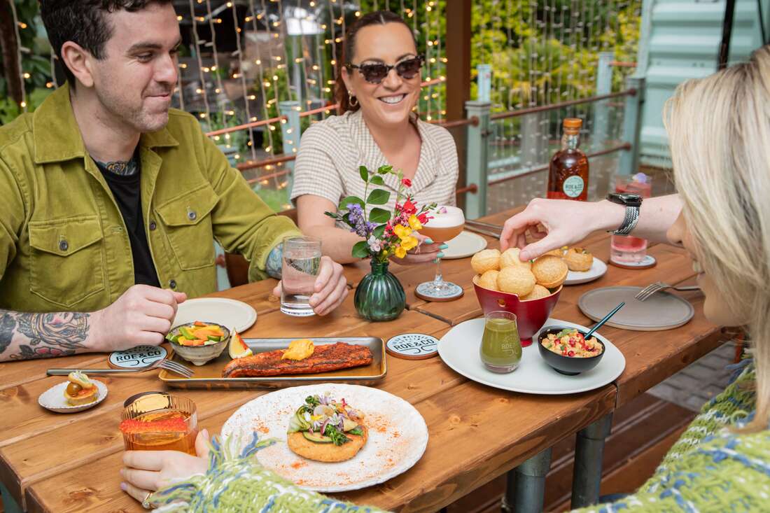 People sitting at a table filled with food at Roe&Co.