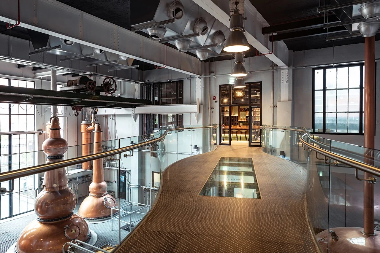 Modern distillery interior with copper stills, glass walkway, and tasting room at Powerhouse Bar, ideal for tours and tastings.