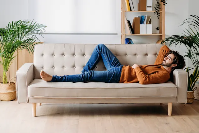 A man relaxing on a beige sofa in a cozy living space.