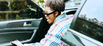 Person getting out of their newly refinanced car, looking very happy