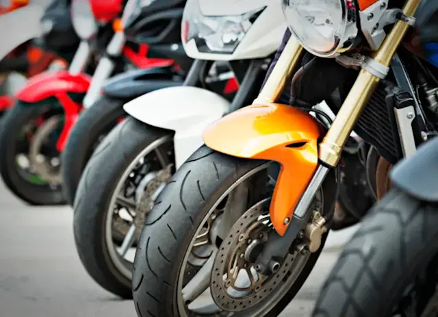 Front wheels and forks of a row of parked motorbikes 
