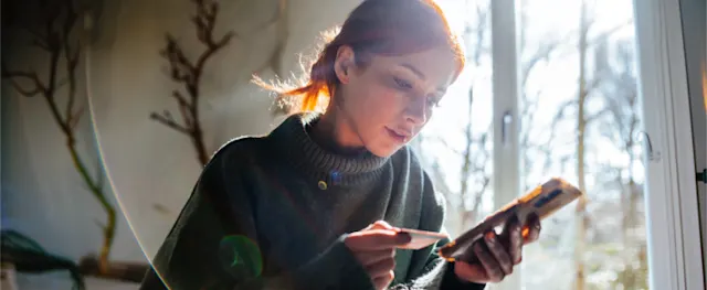A woman reviewing her credit card and finances after debt consolidation.