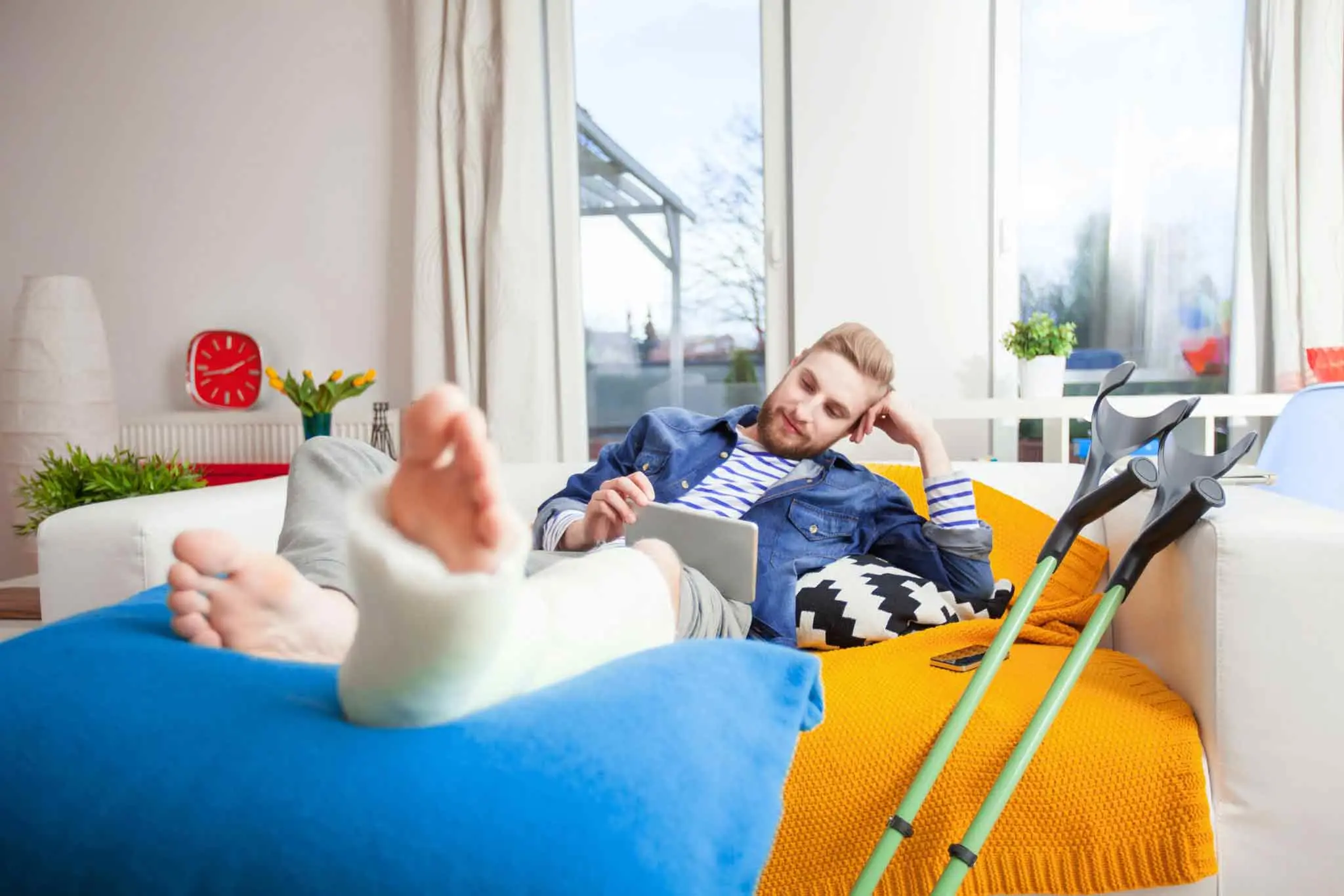 Man with a broken leg lying on bed reading