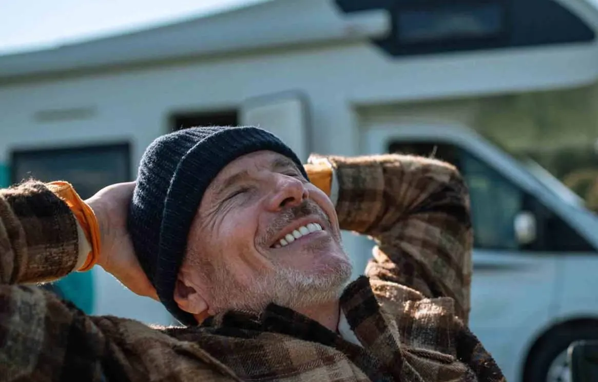 Smiling man in front of camper van 