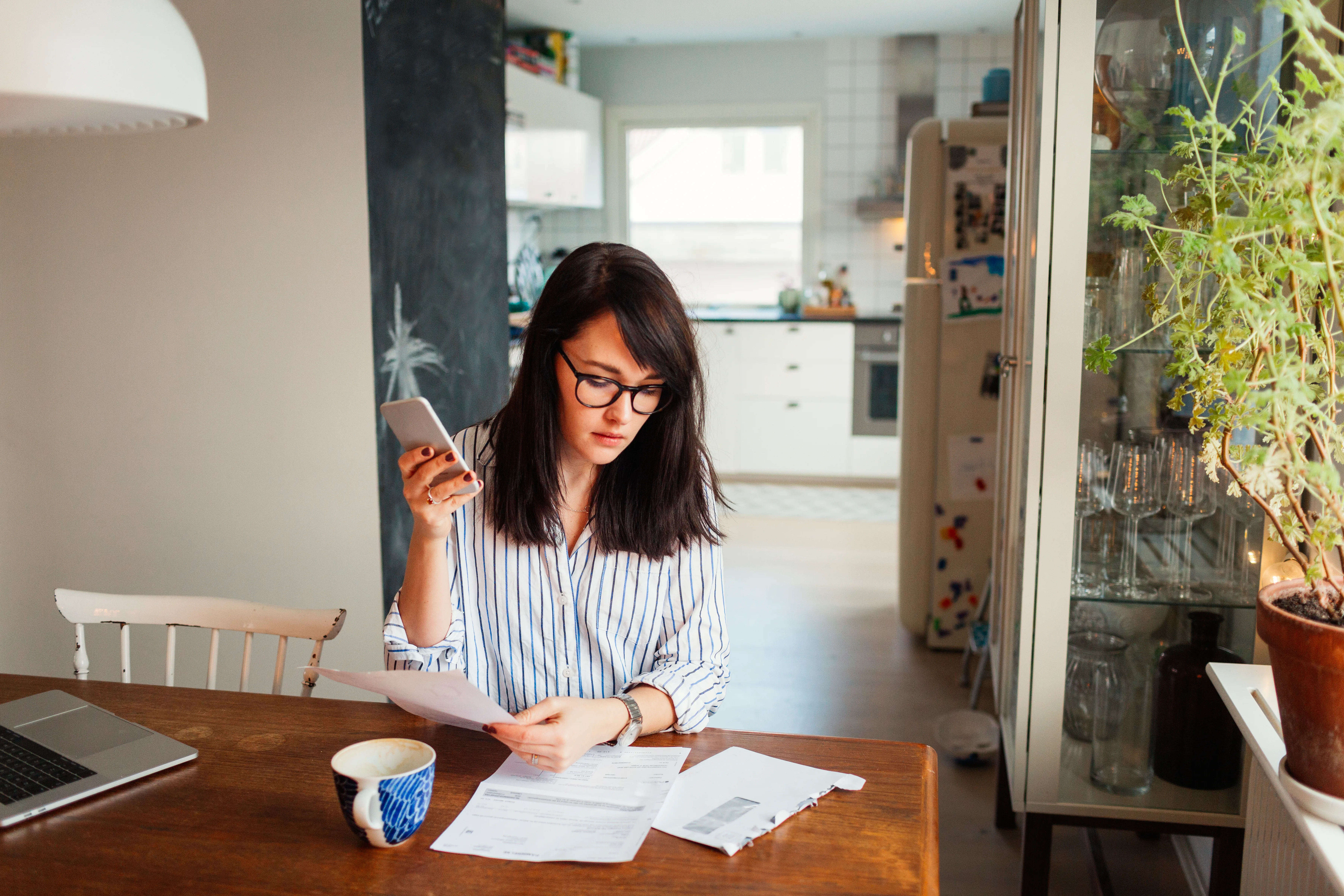 person holding phone looking at paperwork