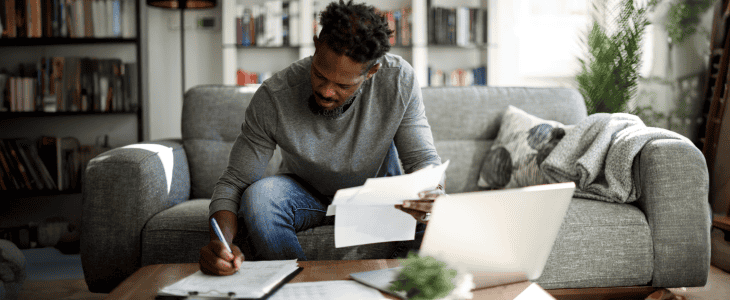 Man sitting on couch weighing out the pros and cons of debt consolidation - OneMain Financial