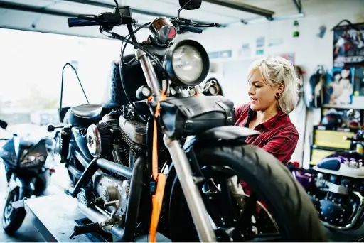 A woman fixing a raised motorcycle