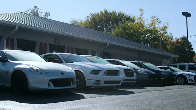 Dealing lot with a line of parked cars in front of office building