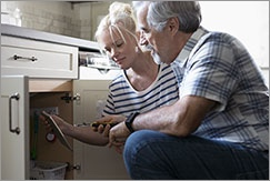 Older couple looking at something in open kitchen cabinet