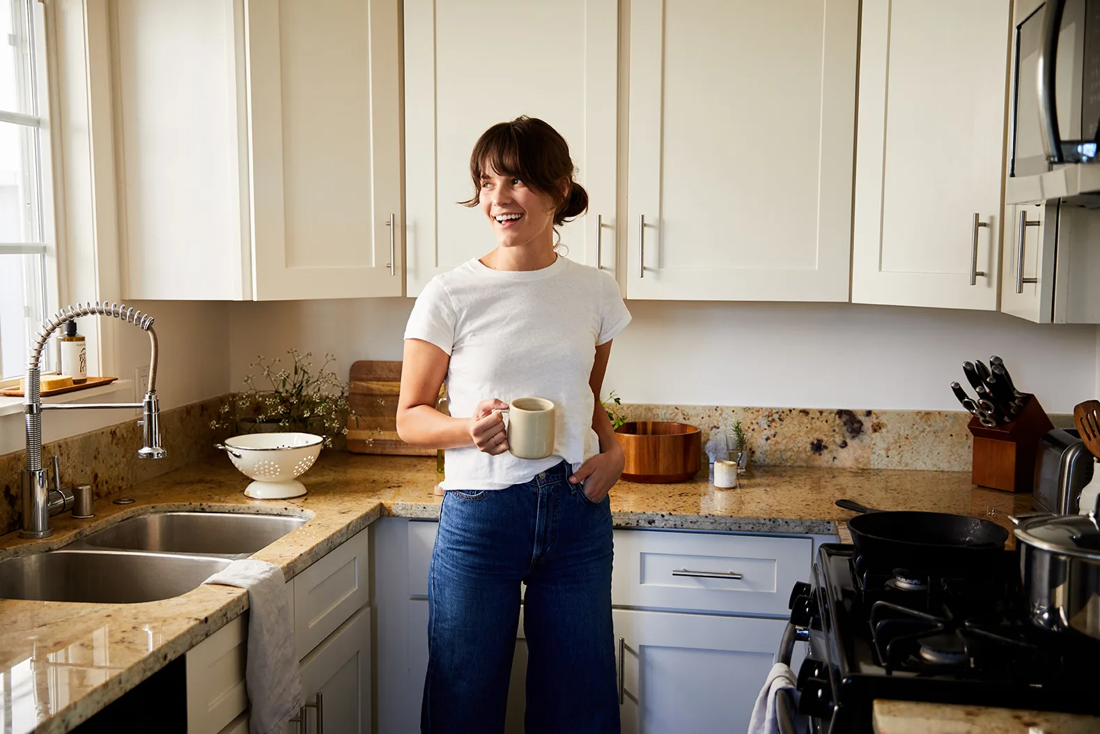 A lady is holding coffee mug in the kitchen
