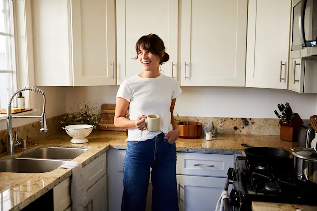 A lady is holding coffee mug in the kitchen