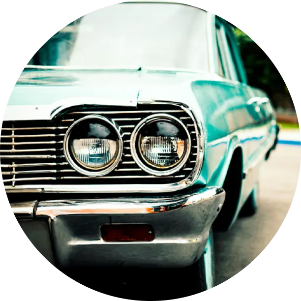 A close-up view of the front grille and headlights of a vintage teal car