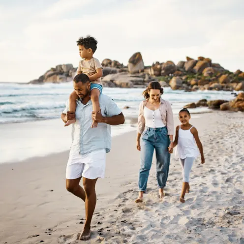 Family walking on the beach with a kid on dad's shoulders