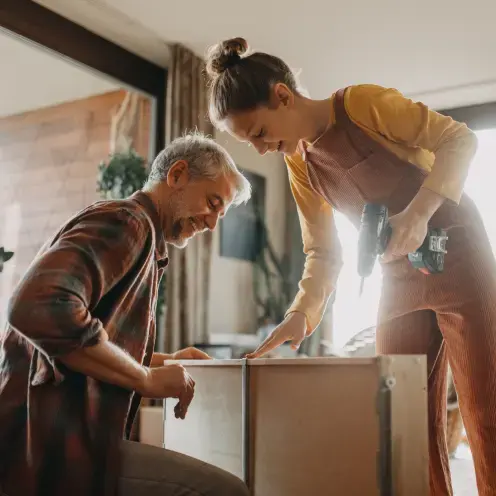 Man and women holding tools and assembling furniture in their living room