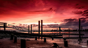 Crimson skies paint the Fraser River at sunset in Delta, BC.