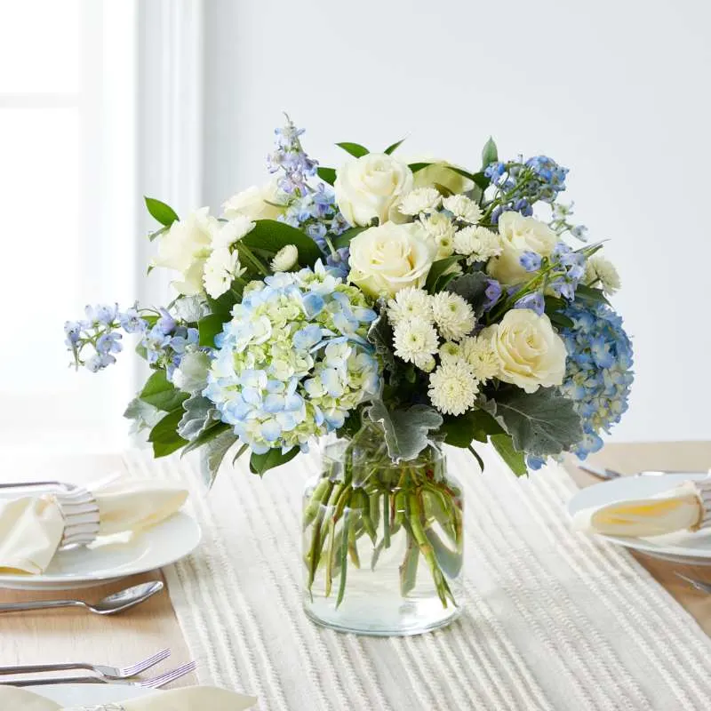 ivory tablescape featuring blue and white bouquet inside a clear vase