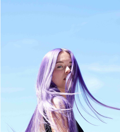 Person with pastel purple hair with a sky background