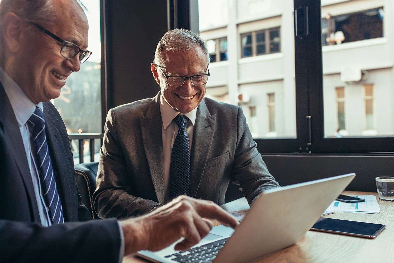 Geschäftspartner arbeiten gemeinsam an einem Laptop in einem Cafe - 3:2