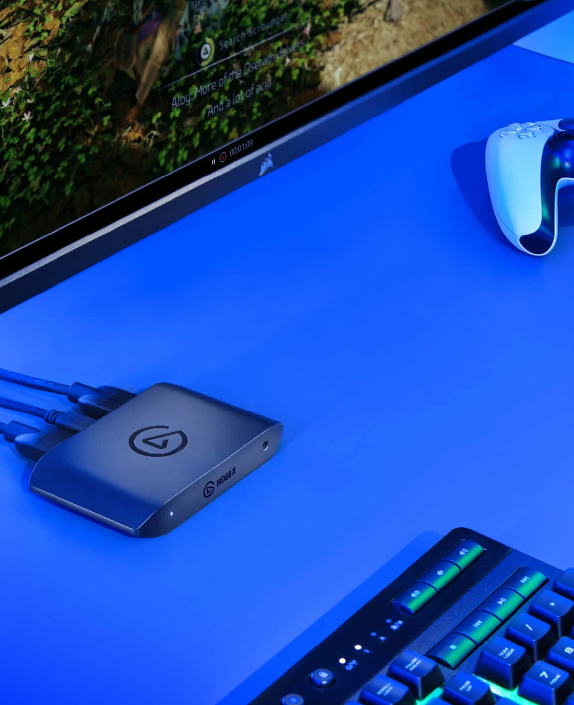 HD60 X on a blue table next to a controller and a keyboard