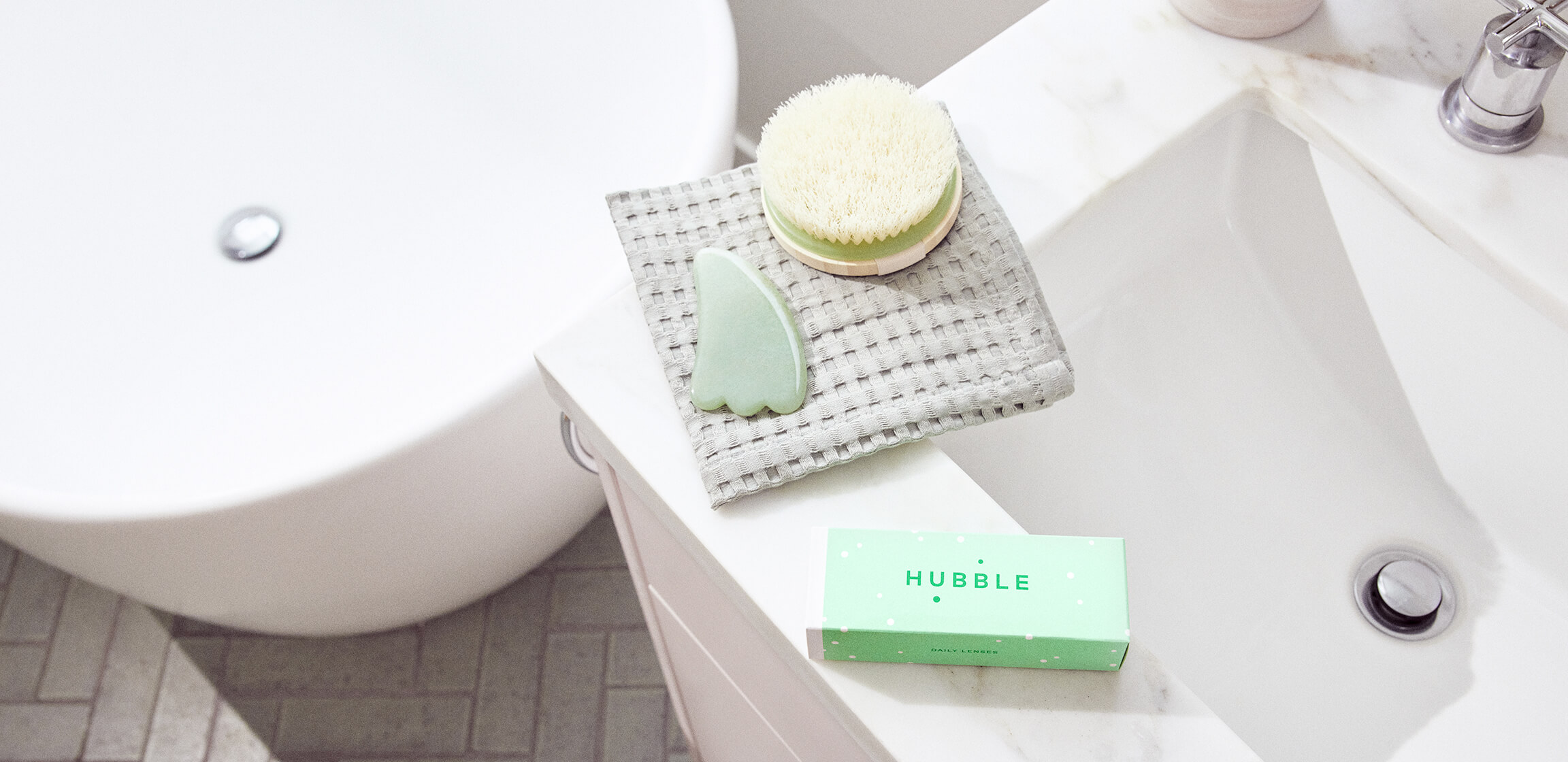 Green box of Hubble Contacts on serene bathroom sink