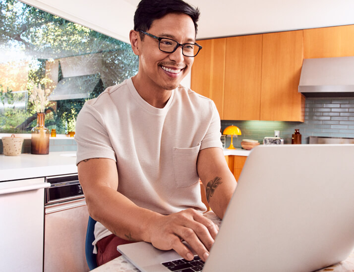 Happy man wearing Hubble eyeglasses working on his laptop at home