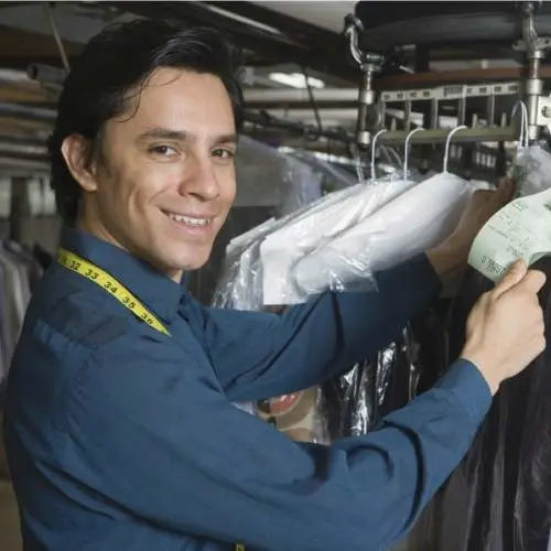 Man smiling while working in a dry-cleaning store