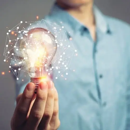 A man holding a glowing light bulb with illustrations of constellations around it