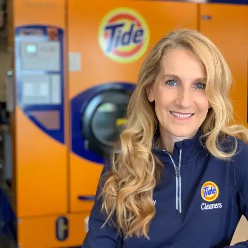 Woman smiling in front of Tide dry-cleaners machine