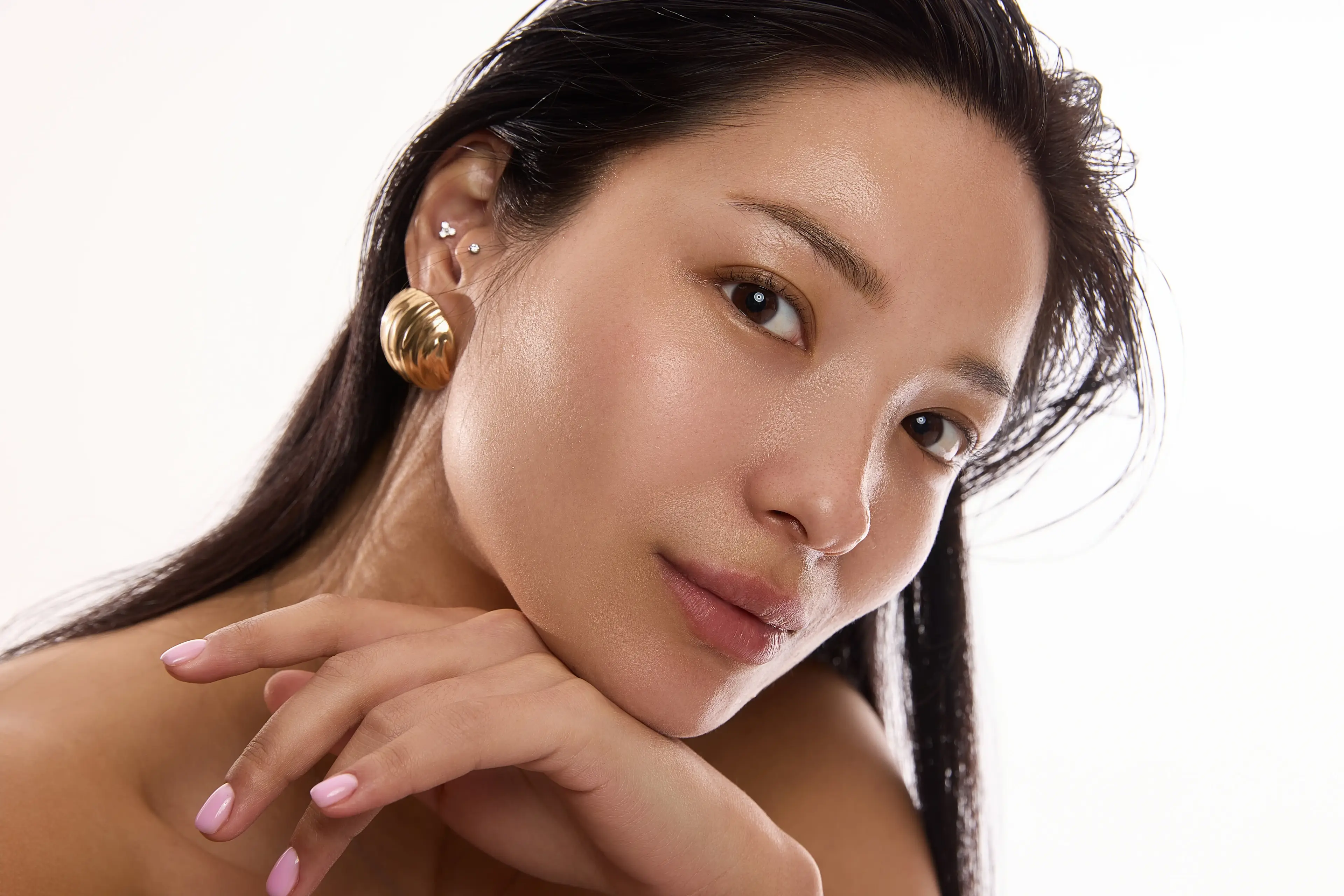 Junge Frau mit strahlender, glatter Haut schaut in die Kamera