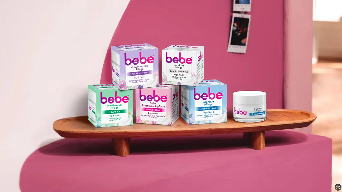 Verpackte Produkte der unterschiedlichen bebe Gesichtspflege liegen gestapelt auf einem Tablett. 