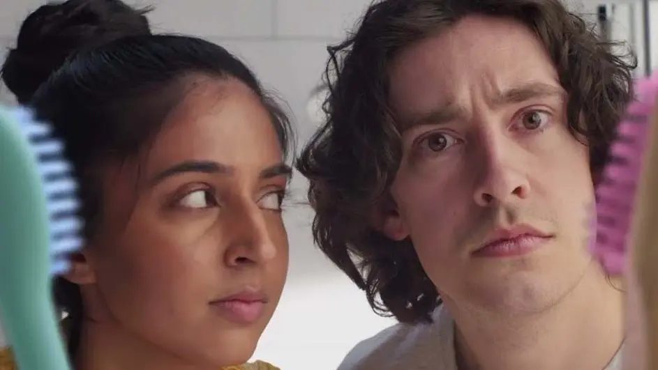 Junge Frau und Junger Mann schauen in die Kamera und halten jeweils eine Zahnbürste