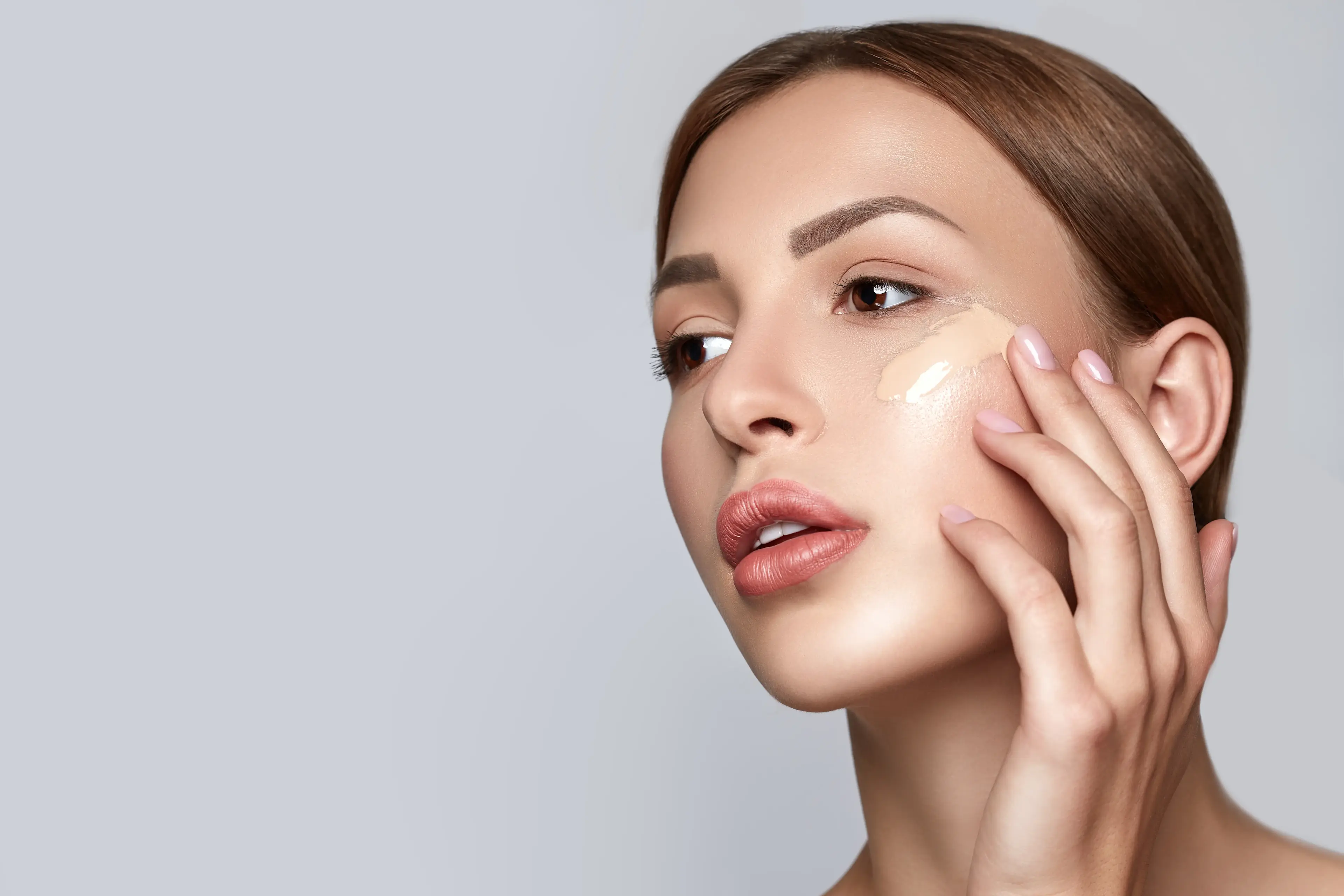 Junge Frau mit gesunder Haut praktiziert Hautpflege und trägt Creme auf ihr Gesicht auf. 