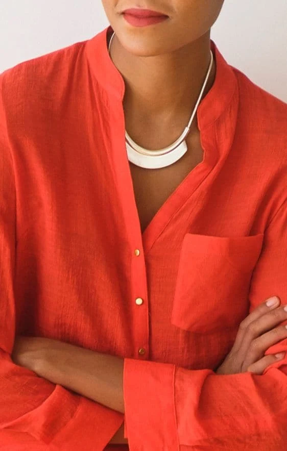 Kırmızı bir bluzu ve parıltılı bir kolyesi olan bir kadın