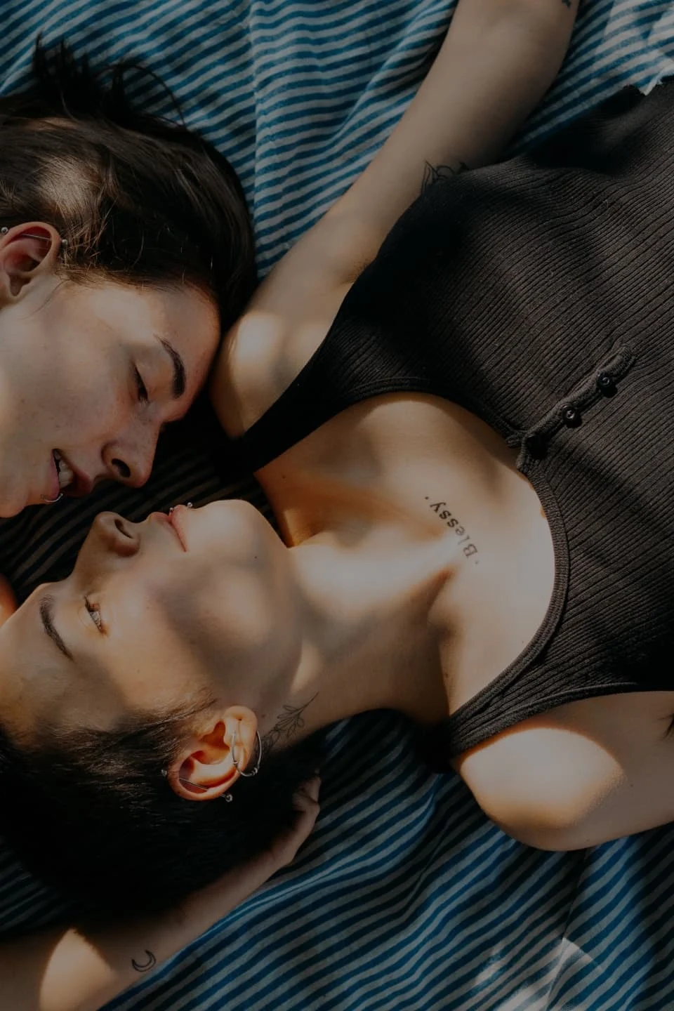 Two women with brown hair lying next to eachother on a blanket