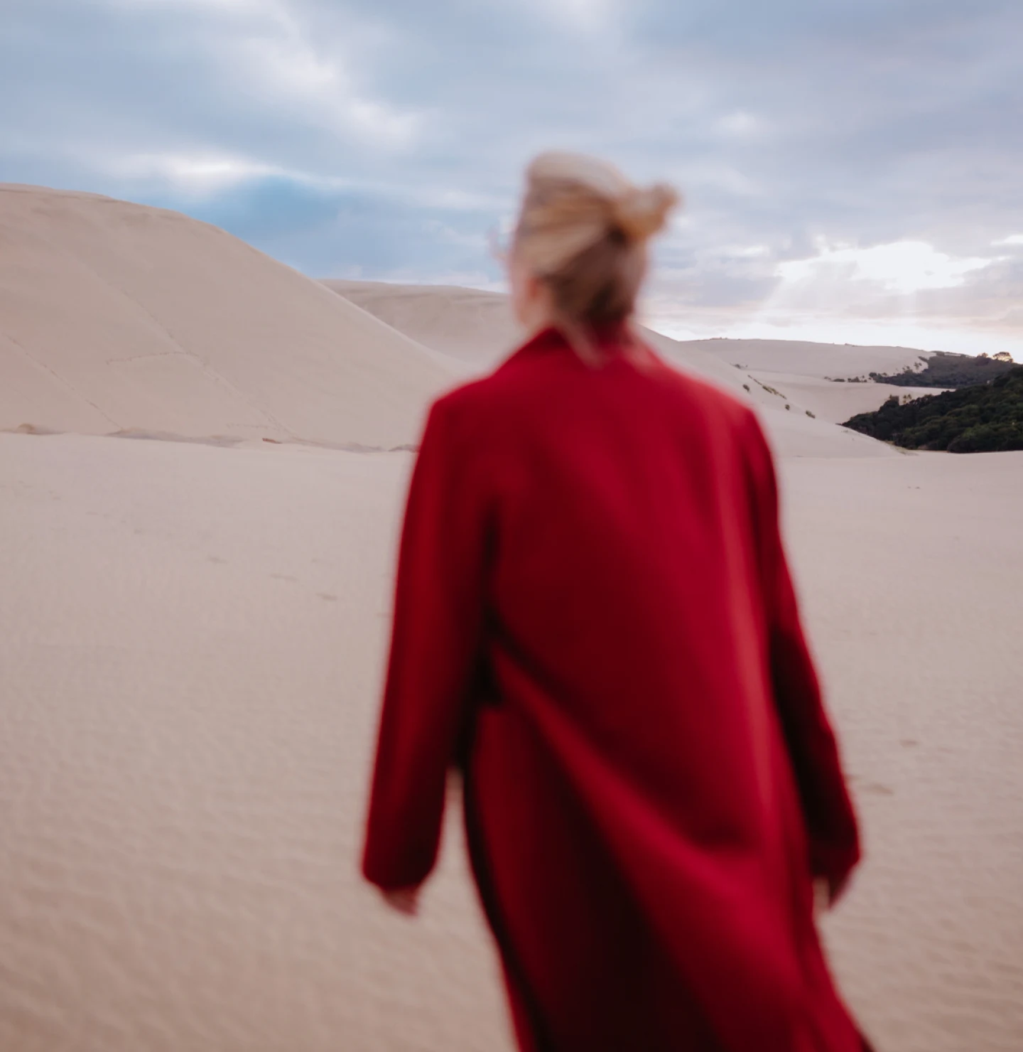 Woman in  red coat walks in the desert