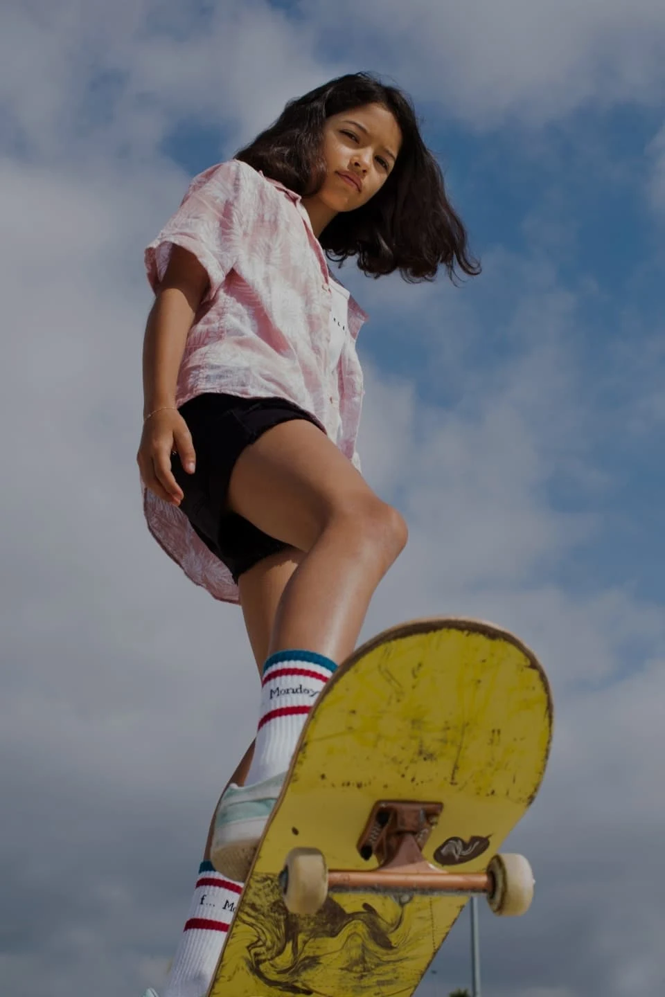 Una ragazza dai capelli castani su uno skateboard giallo